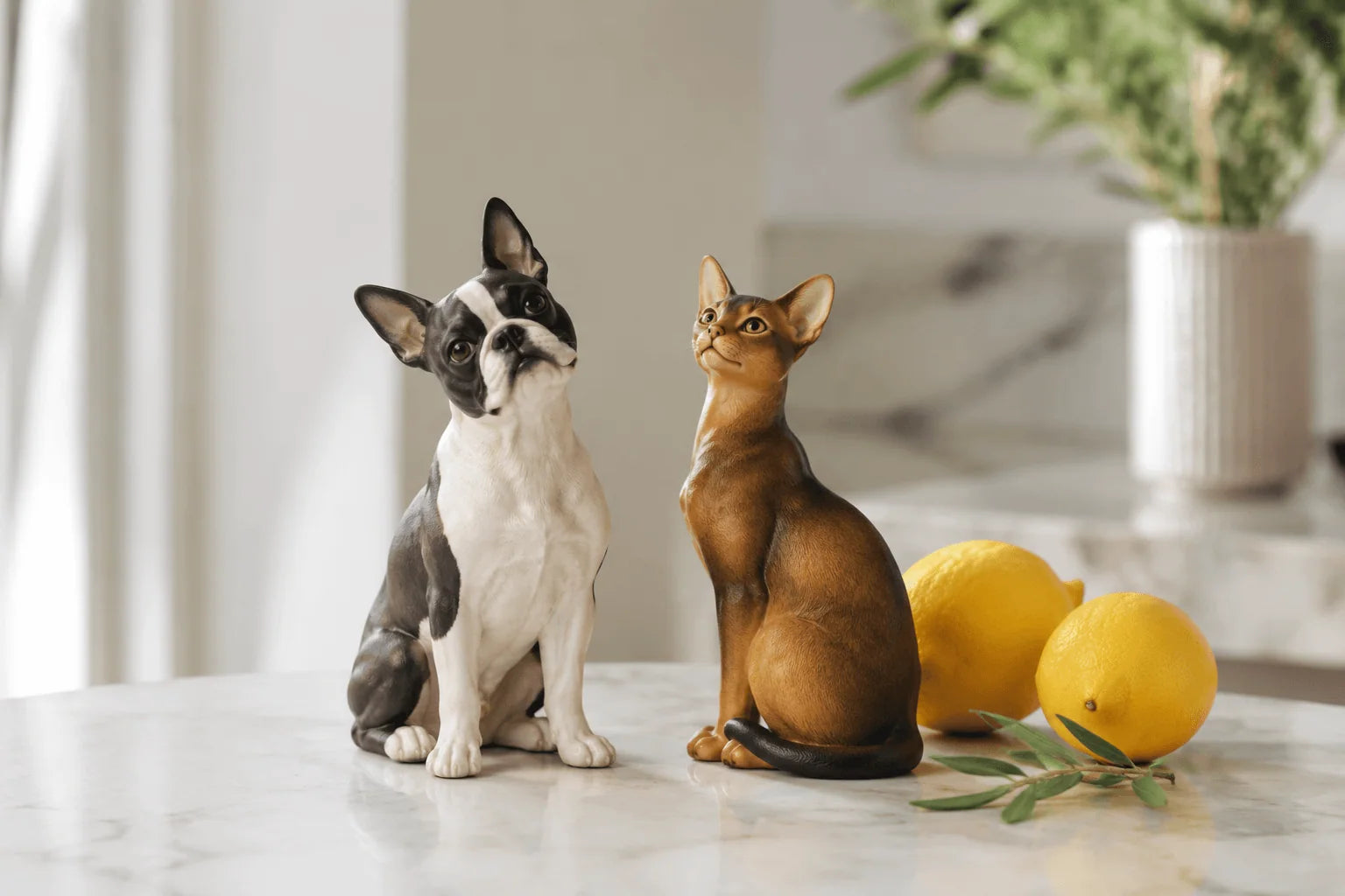 Dog and cat figurines under clean side light with apples and blossom